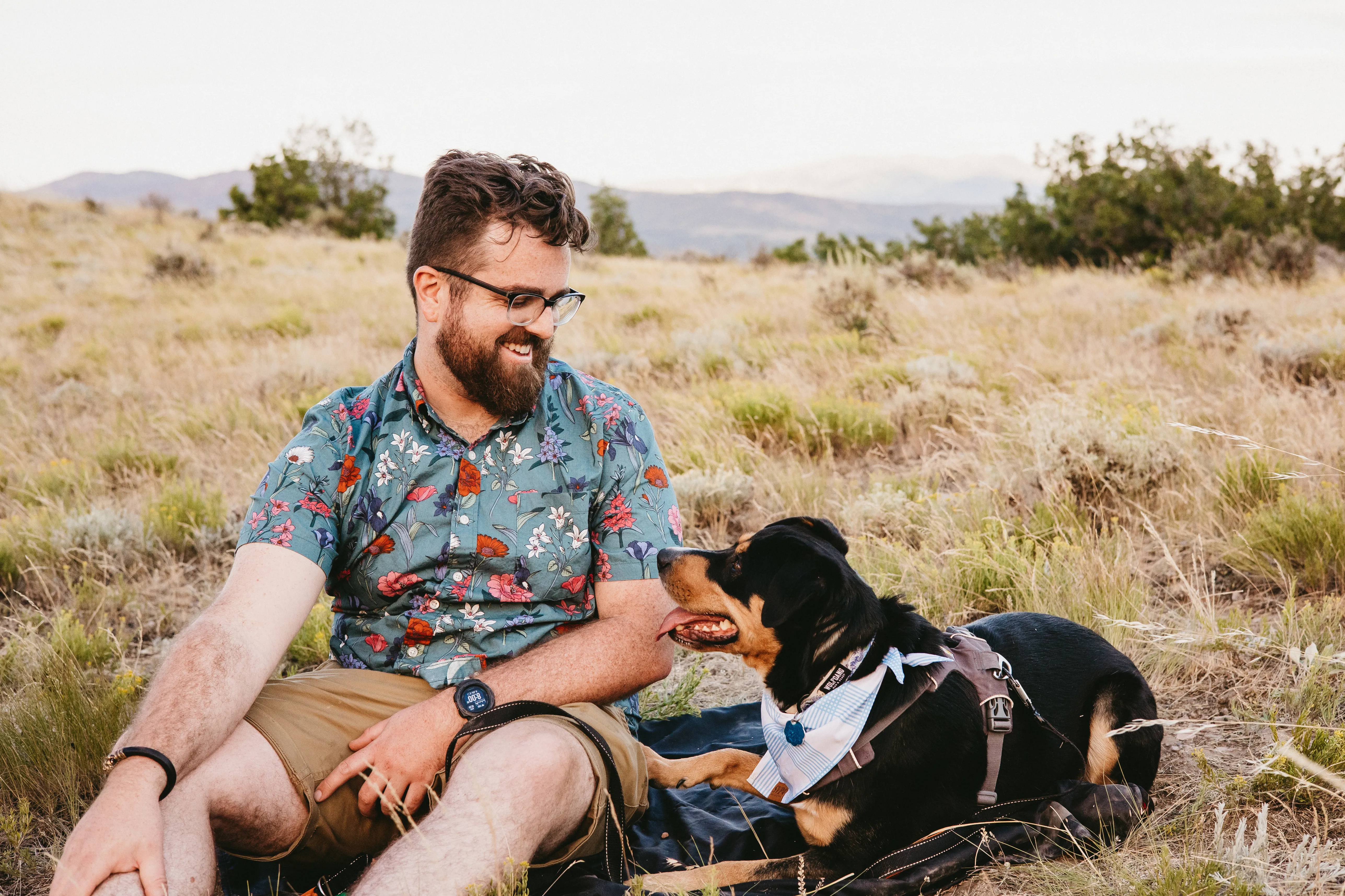 Ty sitting in the sagebrush at golden hour, laughing at his dog